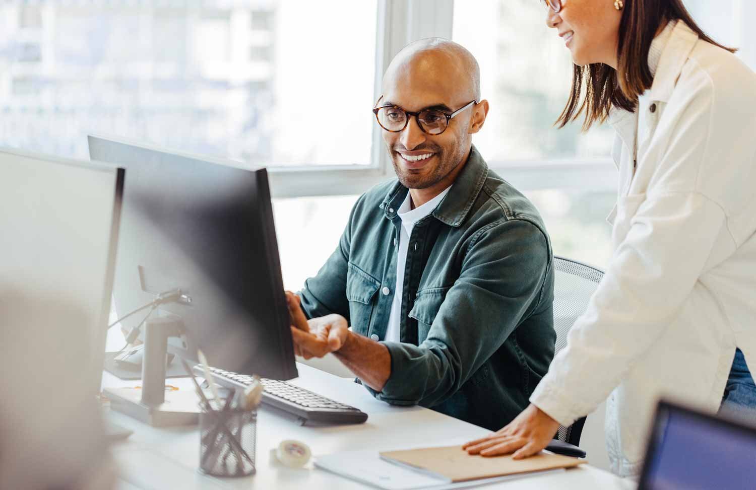 Two colleagues, a man and a woman, engaged in a discussion about HubSpot lead scoring while sitting at their workspace.