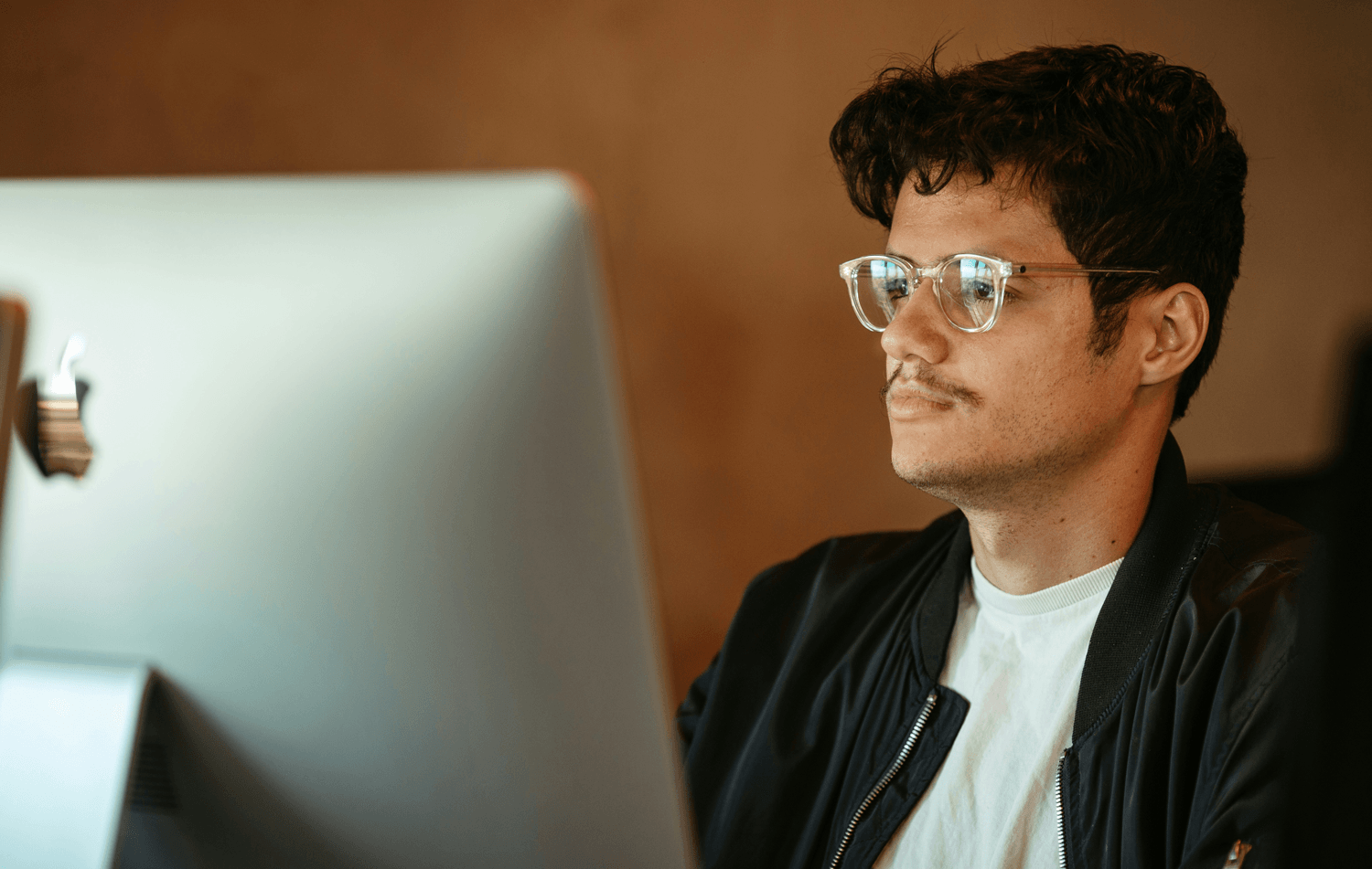 Marketing professional working at a desktop computer, weighing the decision between hiring a full-time or fractional CMO