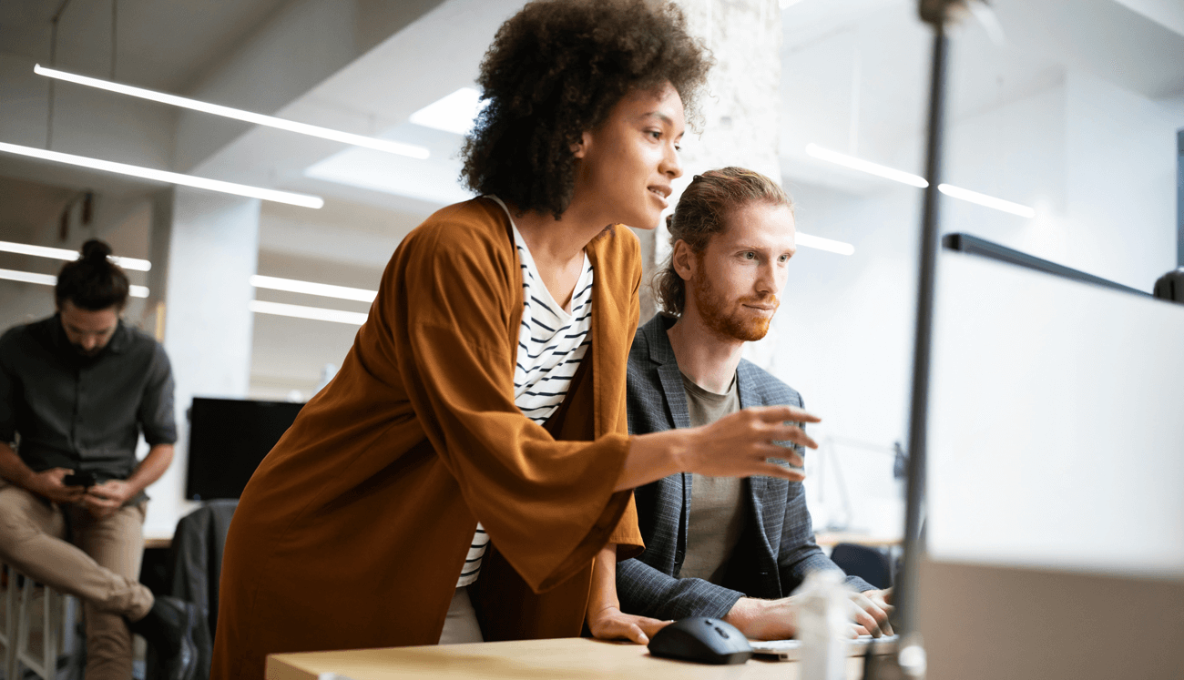 Marketing leader guiding a team member through campaign data on screen