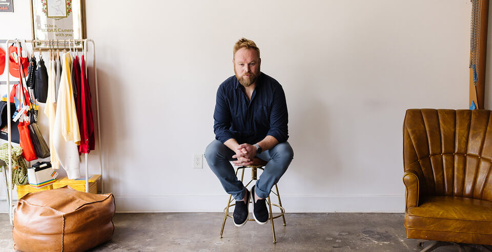 Matthew Deal, HubSpot expert, seated on a stool in his studio with hands clasped.